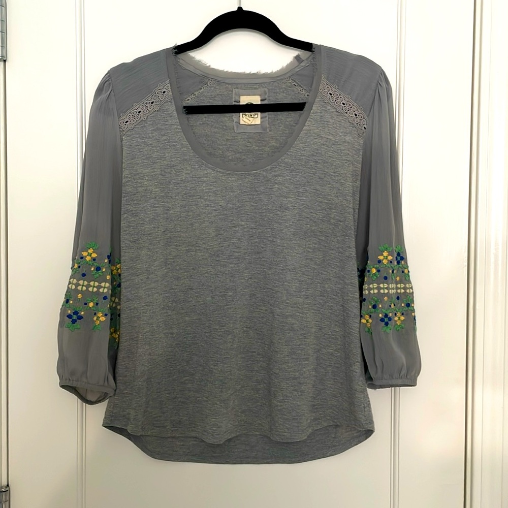 Grey blouse with embroidered detail on sleeve.